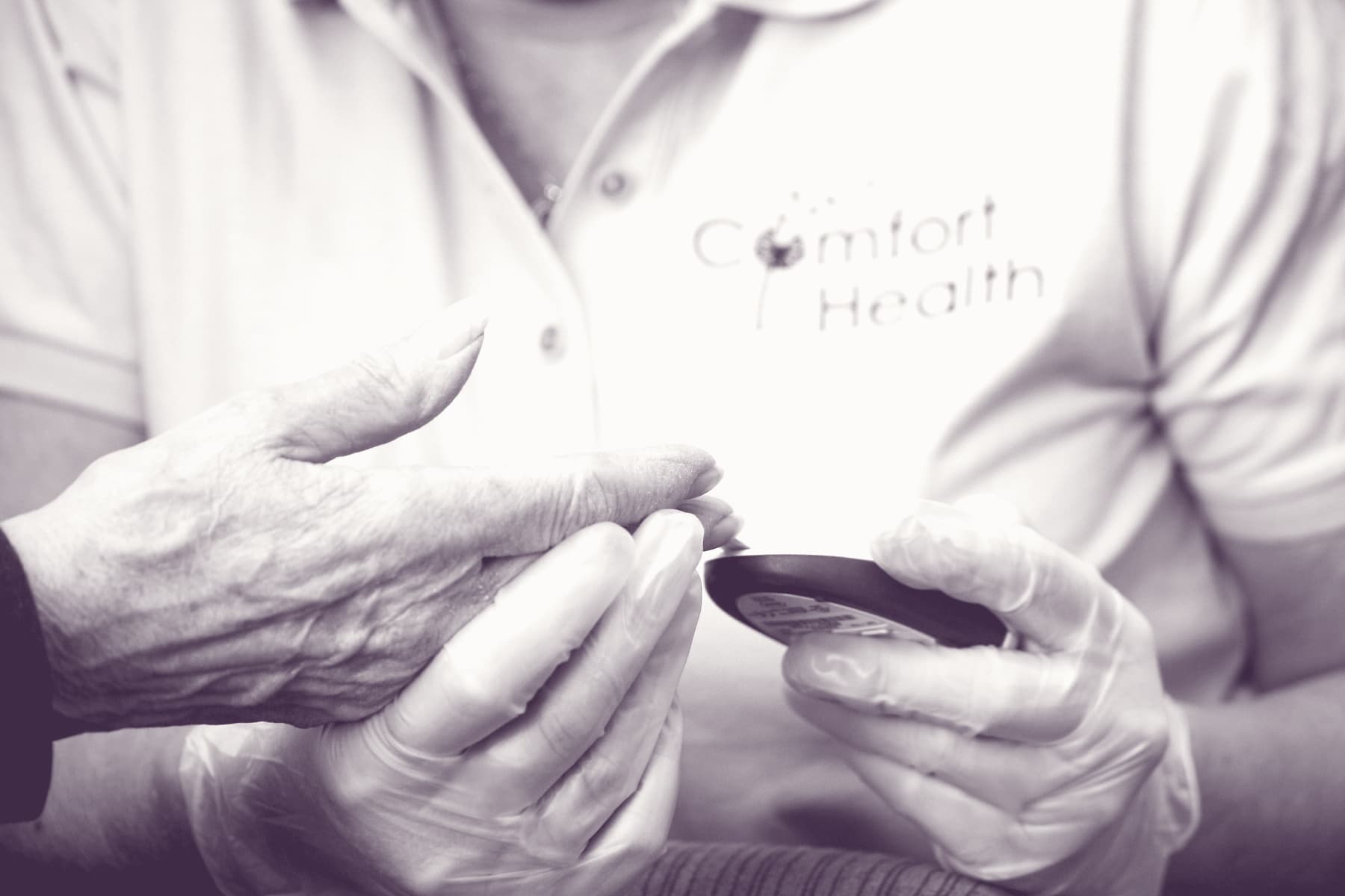 A Comfort Health caregiver checking a client's blood glucose at home.