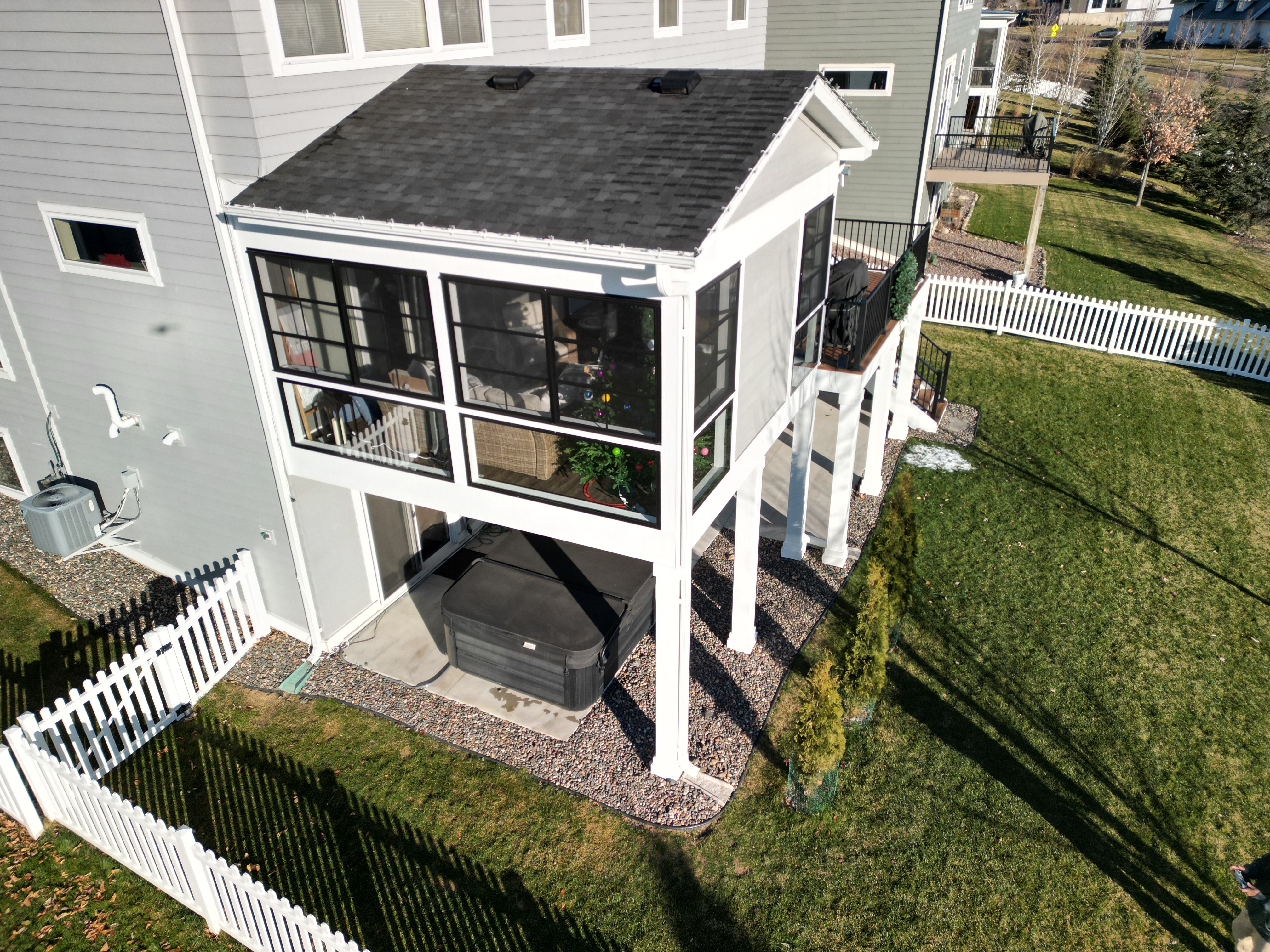 Second-story screened porch and elevated deck over a covered patio with a hot tub, drone view of a Minneapolis Decks rooftop-style build
