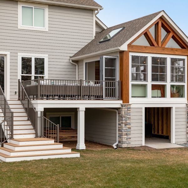 Wayzata back yard — Two-story cedar-trim screened porch + open deck combination, integrated stone columns, full architectural daylight composition.